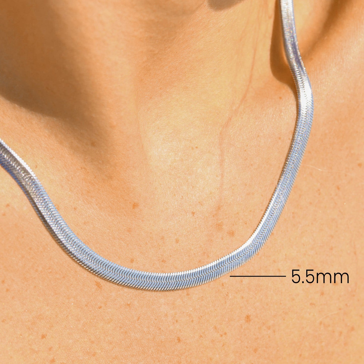 Silver necklace on a person's neck with a measurement label indicating 5.5mm width.