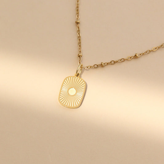 Gold necklace with a sun-shaped pendant on a beige background