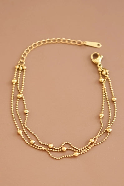 Gold bracelet with multiple chains on a beige background