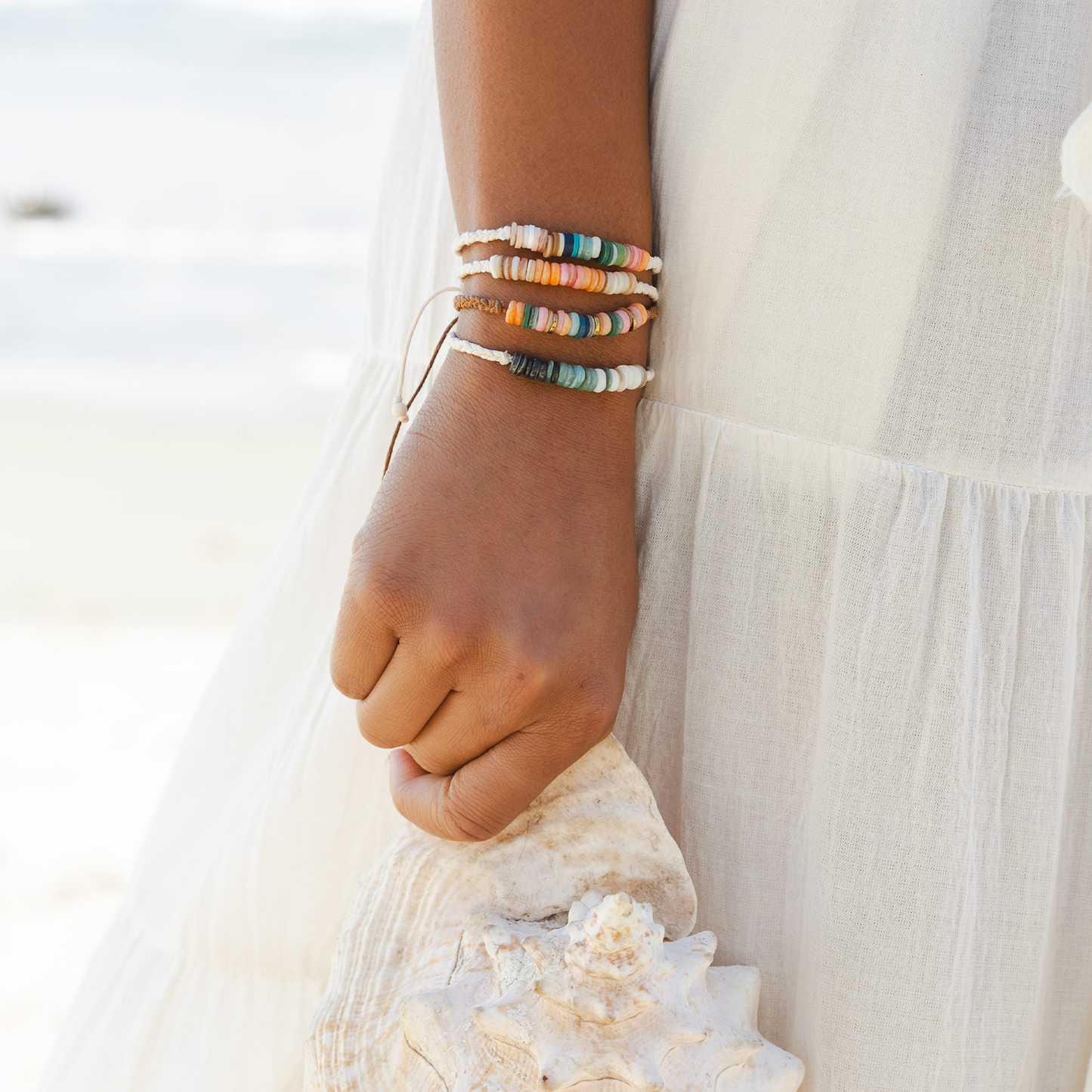Close-up of a wrist wearing colorful bracelets with a blurred natural background