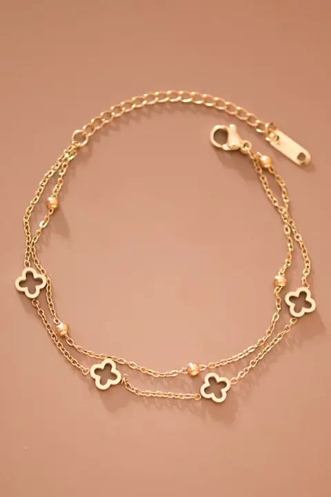 Gold bracelet with clover charms on a beige background