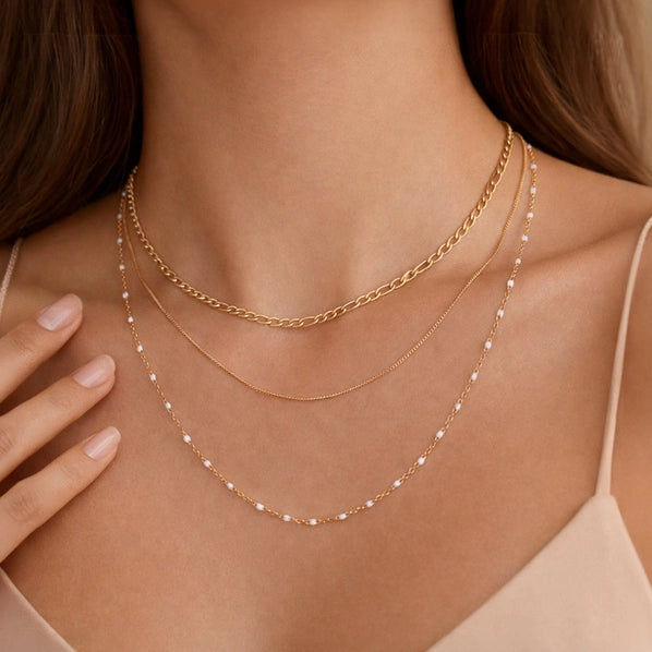 Gold chain three layer necklace with small white beads worn by a person