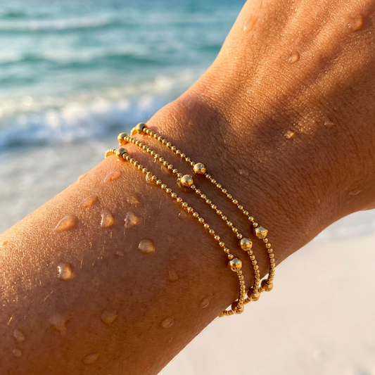 Gold bracelet on a wrist with ocean in the background