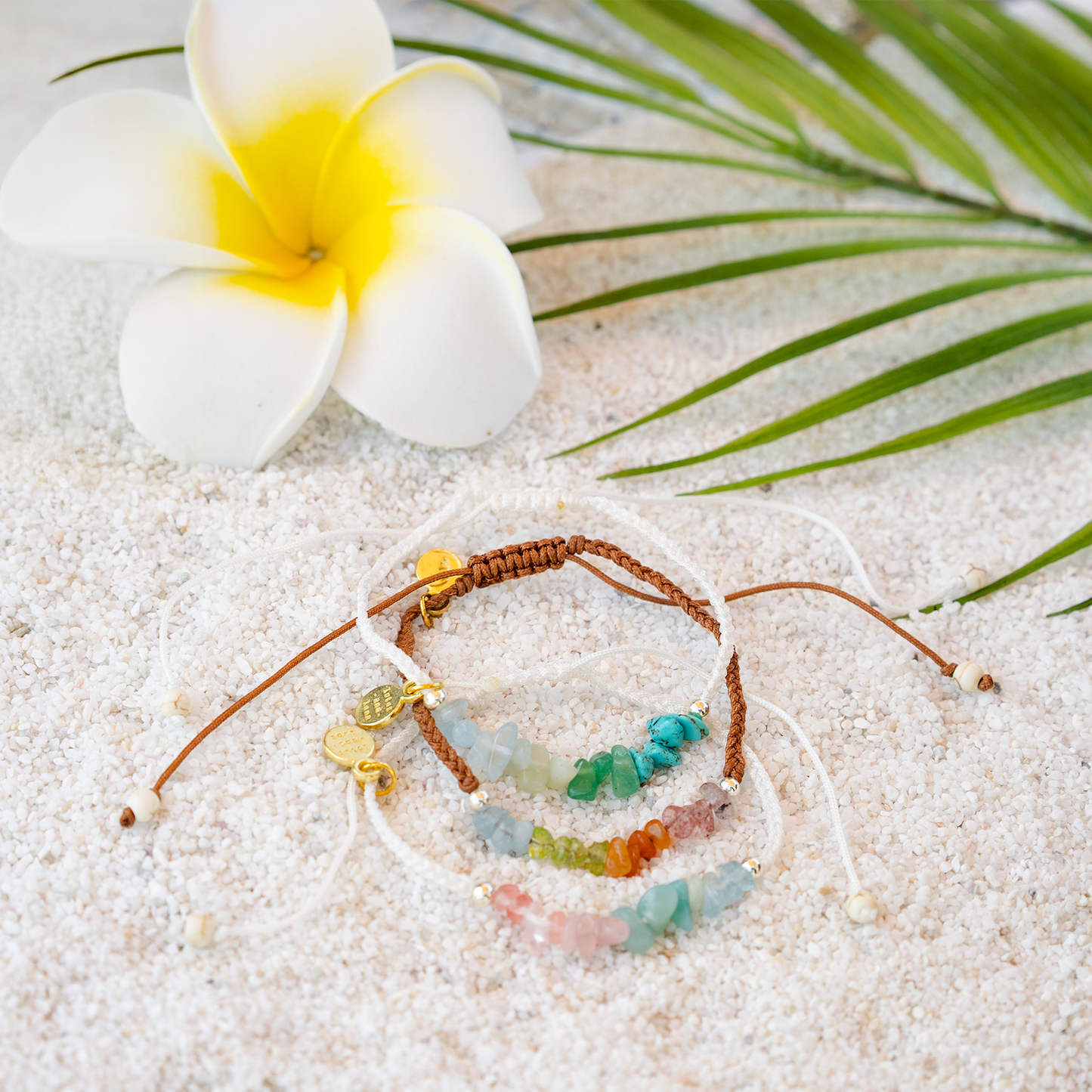 Bracelet with colorful beads on sand with a flower and leaf