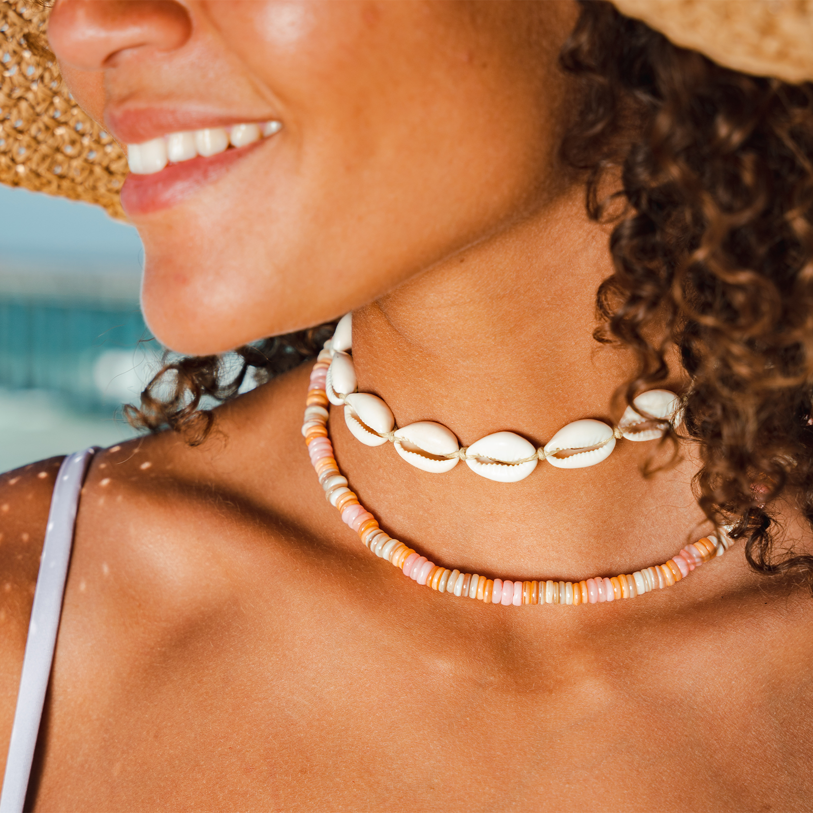 Woman wearing a shell necklace with a blurred beach background