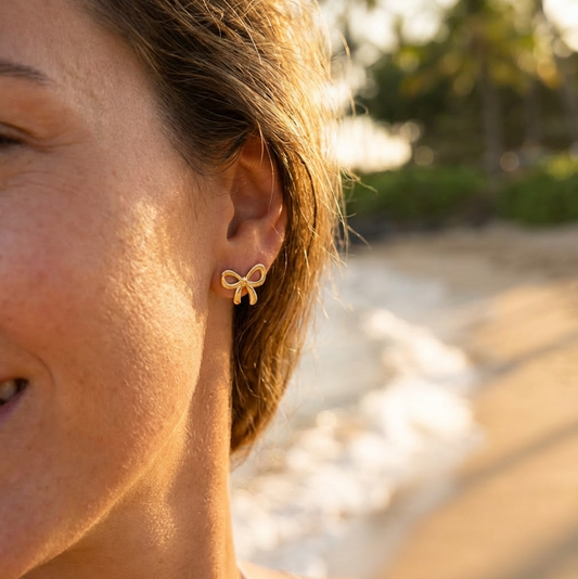 Close-up of a person wearing a bow-shaped earring on a beach.