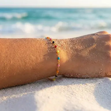 Colorful beaded bracelet on a person's wrist with a blurred beach background