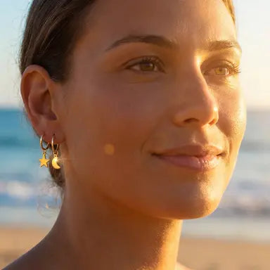 Woman with crescent moon and star-shaped earrings on a beach at sunset