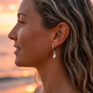 Woman wearing a silver conch shell earring with a sunset in the background