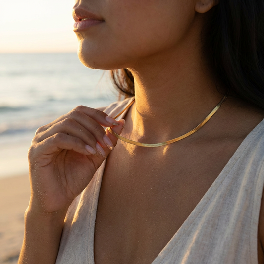 Woman wearing a gold necklace on a beach at sunset
