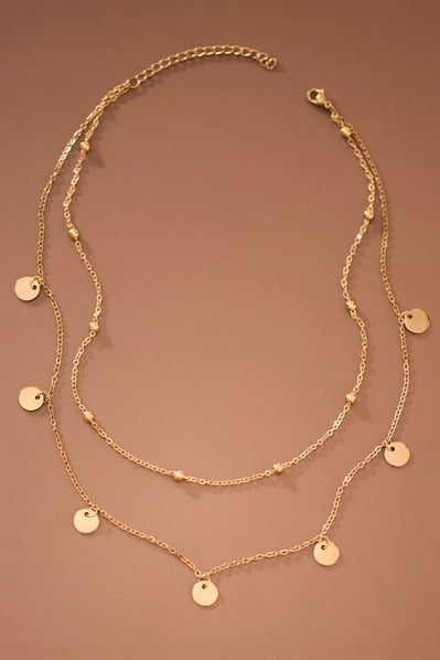 Gold necklace with round pendants on a brown background