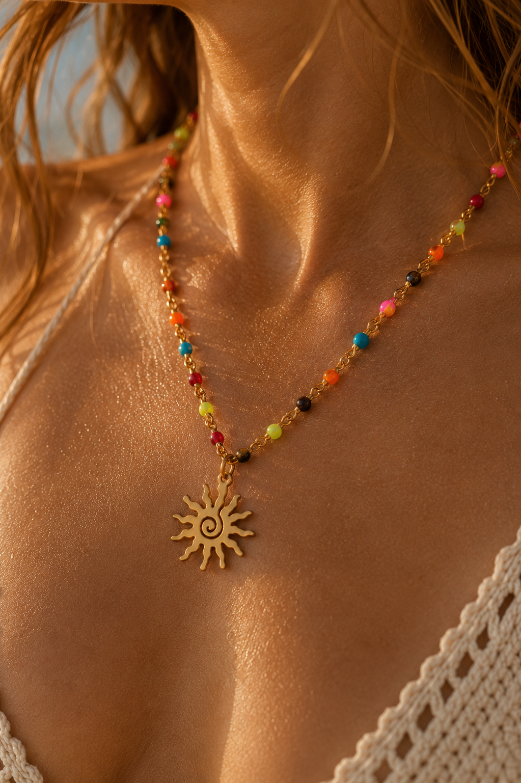 Gold and colorful beaded necklace with spiral sun pendant on a woman with long hair.