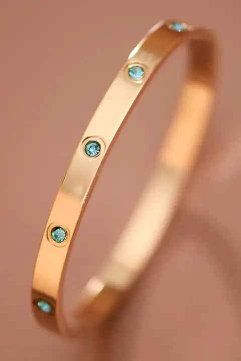Gold bracelet with turquoise stones on a brown background