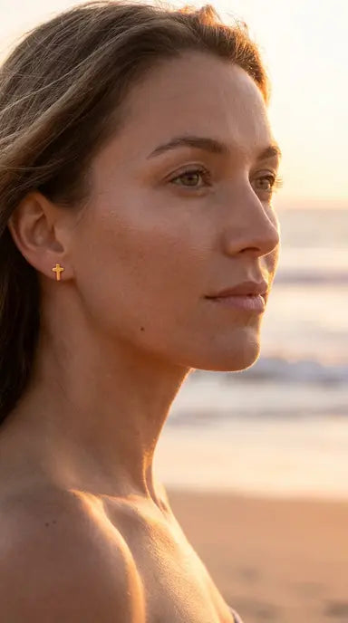 Woman with a cross earring on a beach at sunset