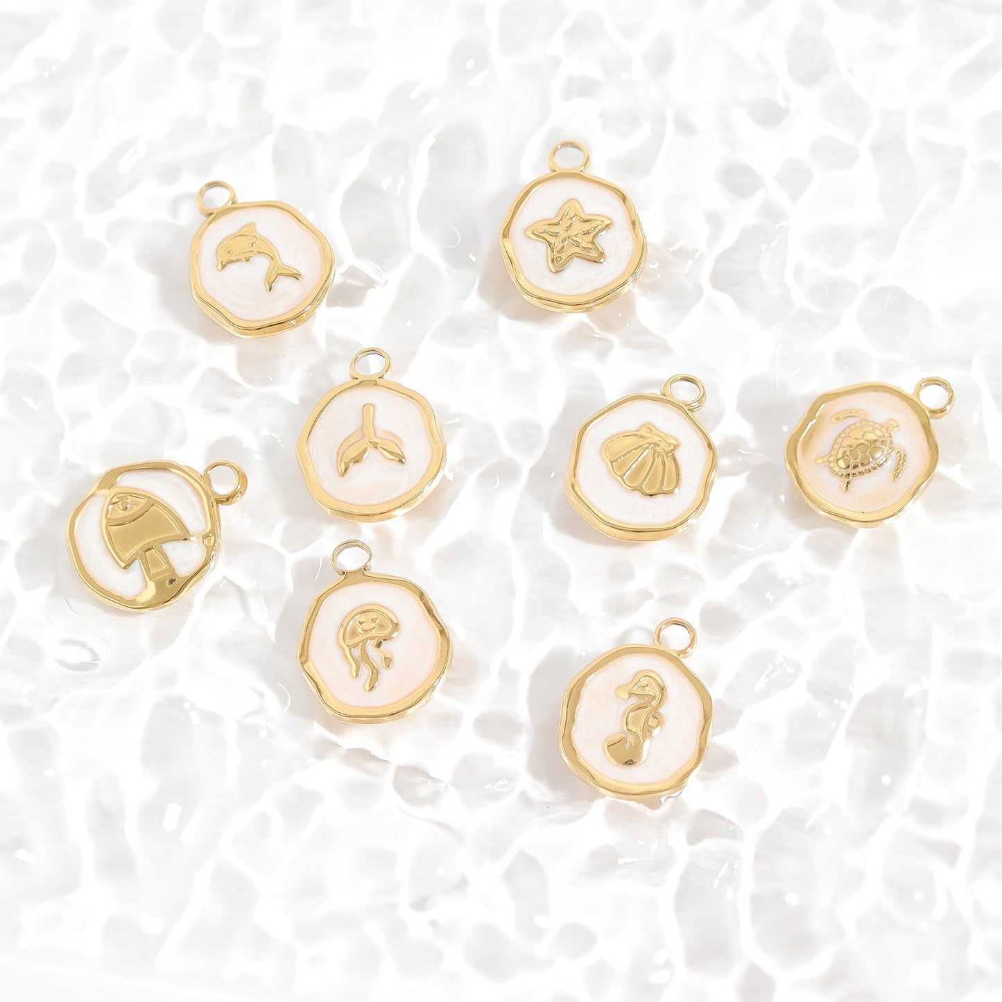 Various circular gold charms with various sea creatures in the center on a textured white surface