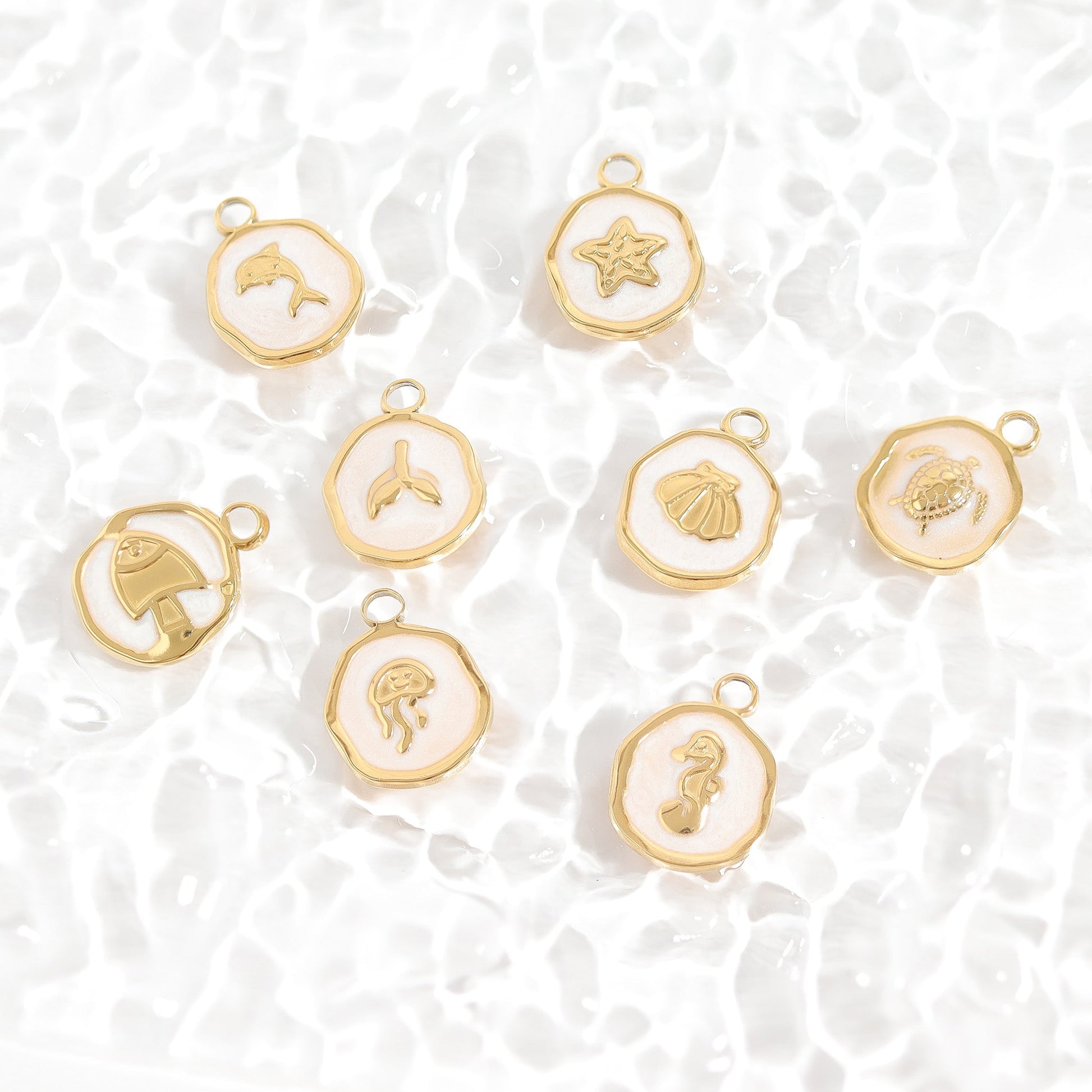 Various circular gold charms with various sea creatures in the center on a textured white surface