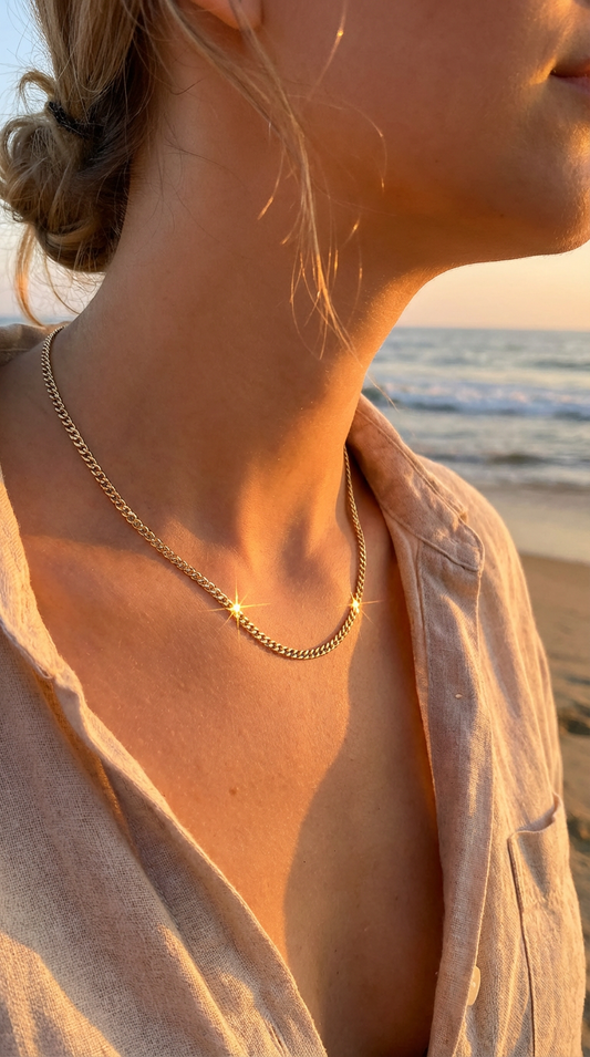 Person wearing a gold diamond cut curb chain necklace on a beach