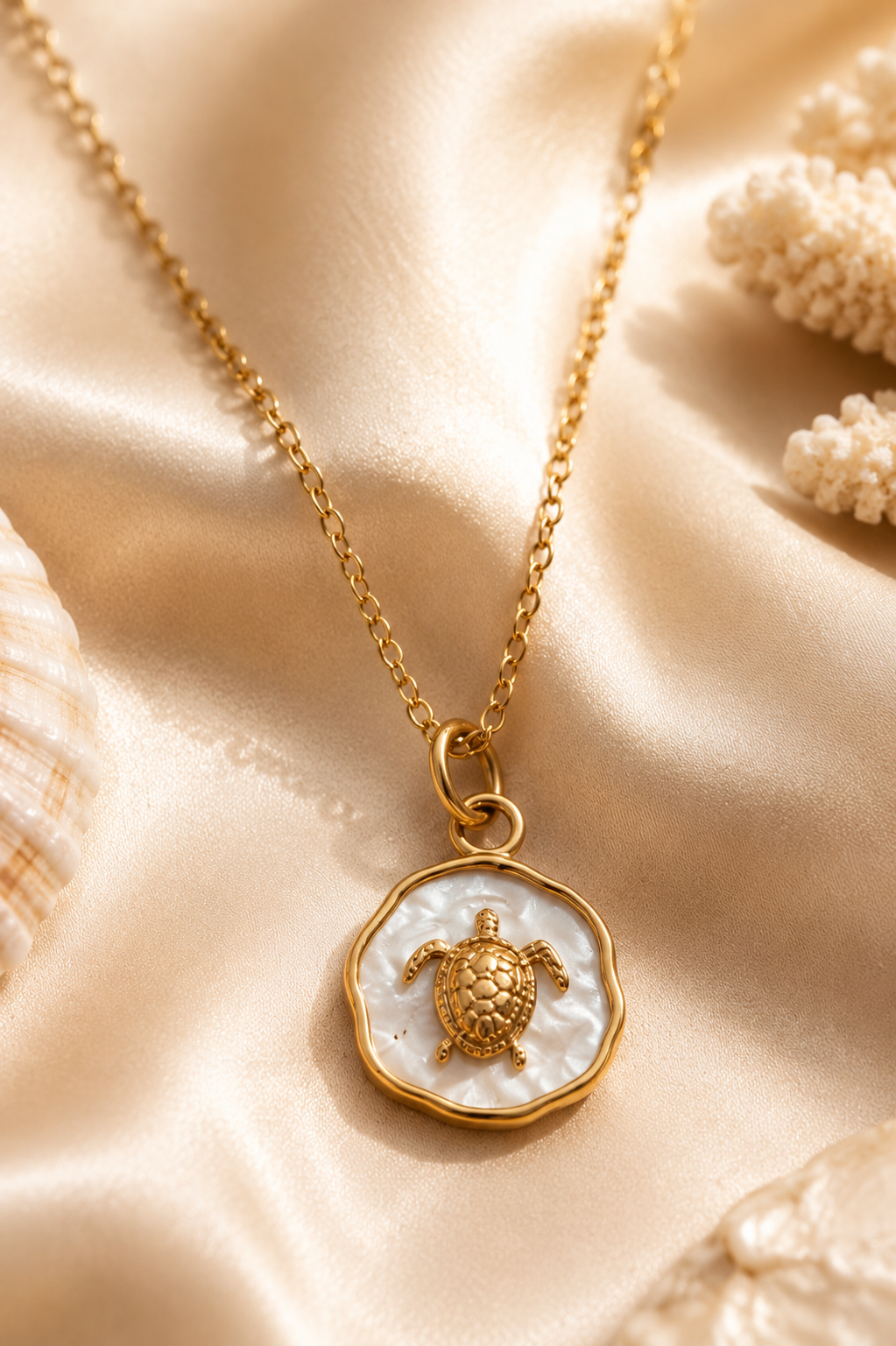 Gold chain with sea turtle pendant lying on satin cloth.