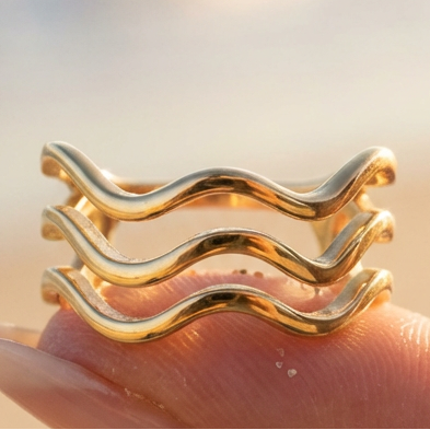 Gold wavy ring on a finger with a blurred background