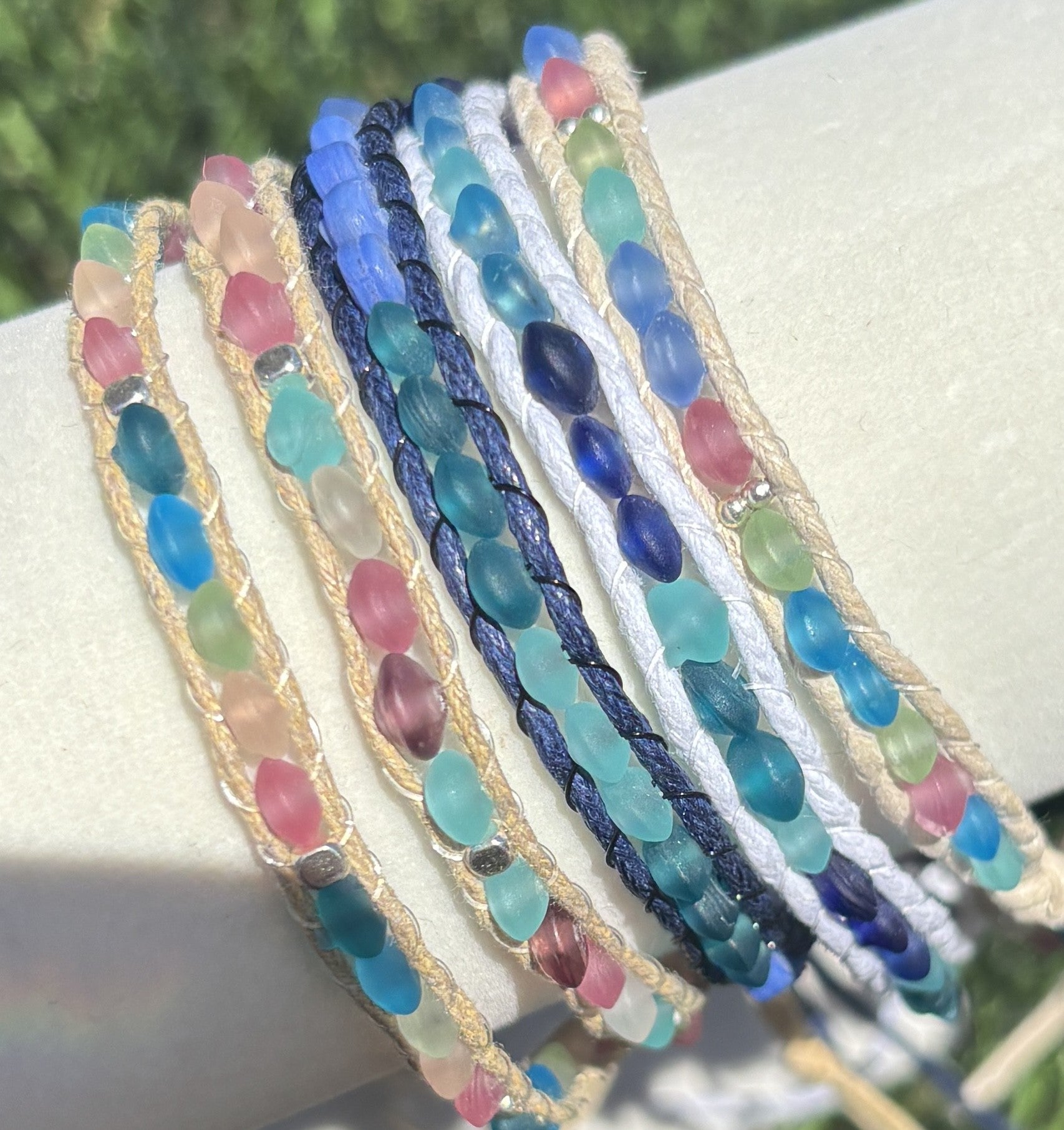 Set of colorful beaded bracelets on a white surface with a blurred natural background