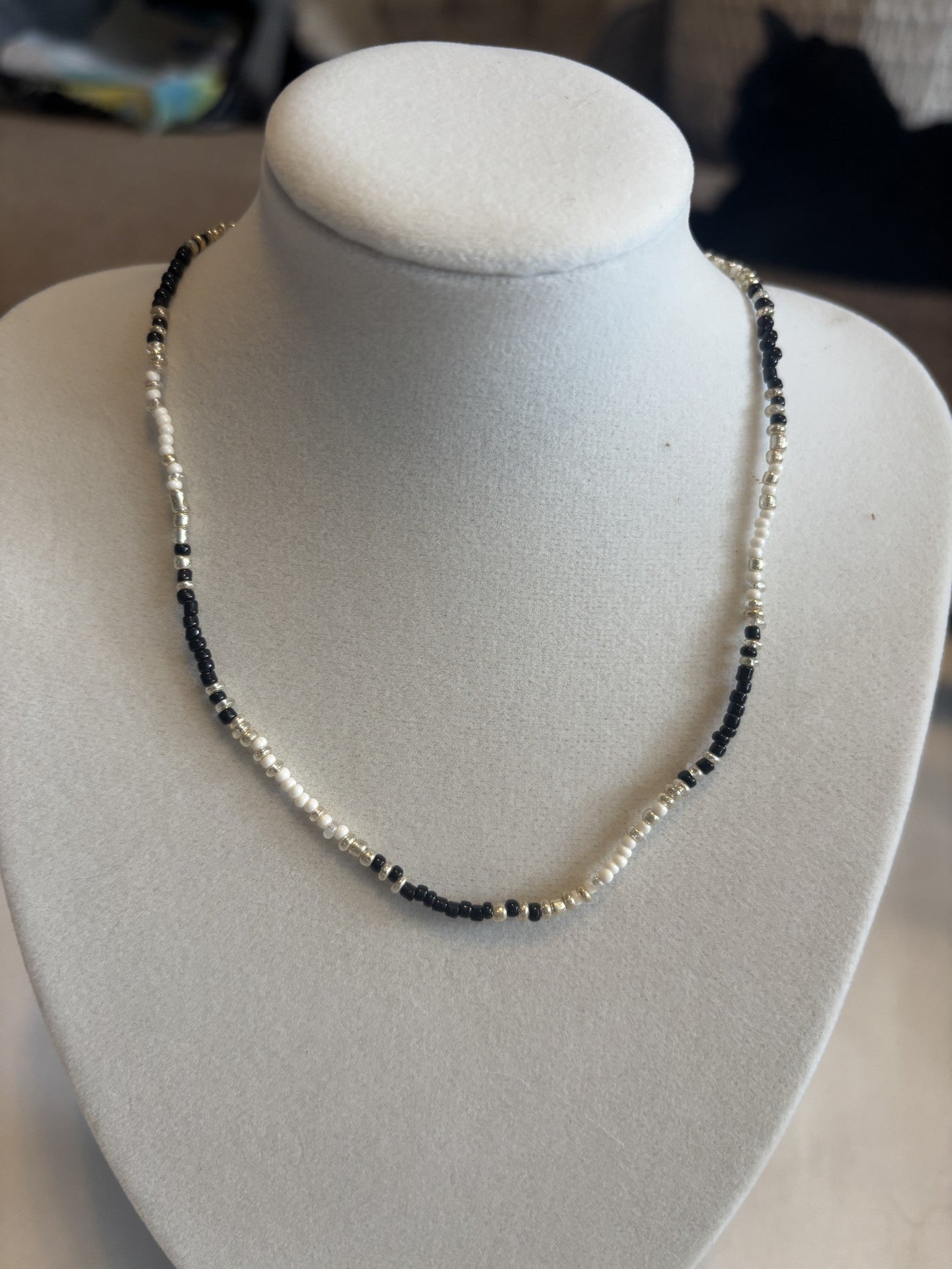 Necklace with black and white beads on a gray mannequin bust.