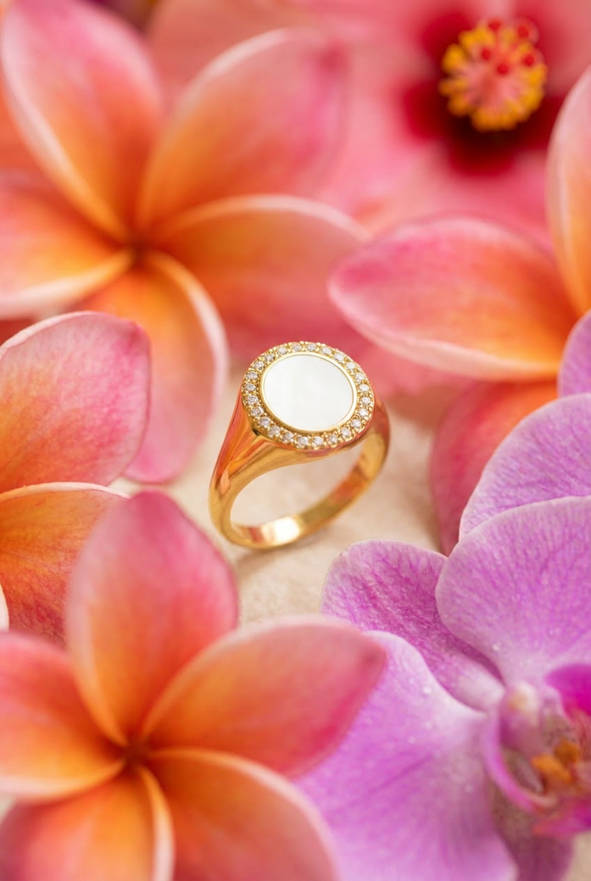 Gold signet ring with white gemstones surrounded by pink and purple flowers.