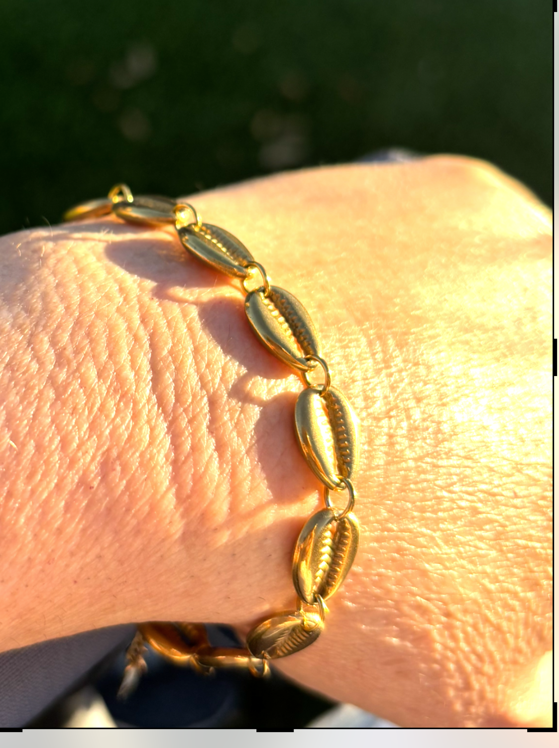 Gold bracelet on a wrist with a blurred natural background