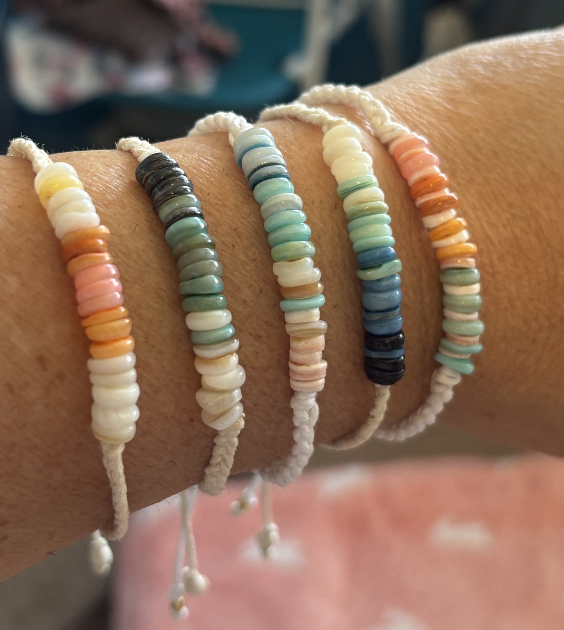 Close-up of a wrist wearing multiple beaded bracelets with a blurred background