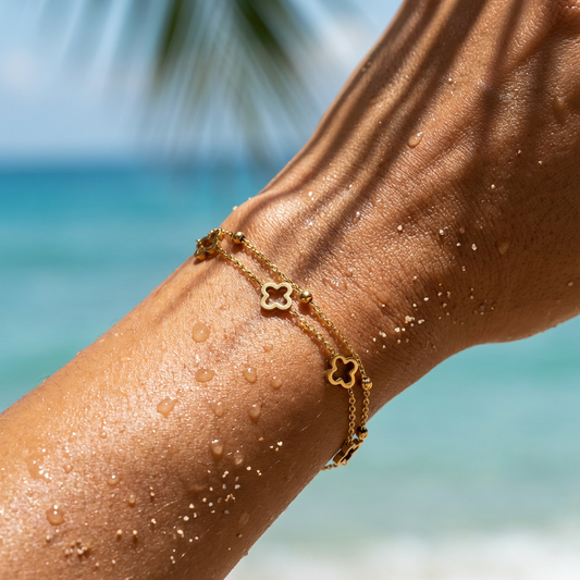 Gold layered bracelet on a person's wrist with a blurred beach background